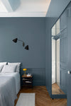 Chambre aux murs bleu couture et bleu zingueur Libéron, avec lit clair, parquet en chevrons et placard assorti.