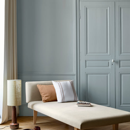 Salon aux murs bleu couture Libéron, avec méridienne écrue, portes assorties, coussins terracotta et parquet clair.