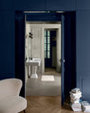 Passage aux murs 163 Faubourg bleu maritime et lait d’amande Libéron, avec fauteuil crème, portes bleues et lavabo blanc.