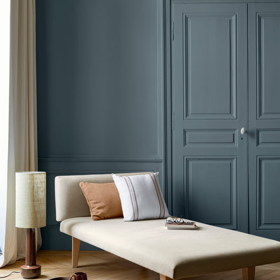 Salon aux murs bleu zingueur Libéron, avec méridienne écrue, portes assorties, coussins terracotta et parquet clair.