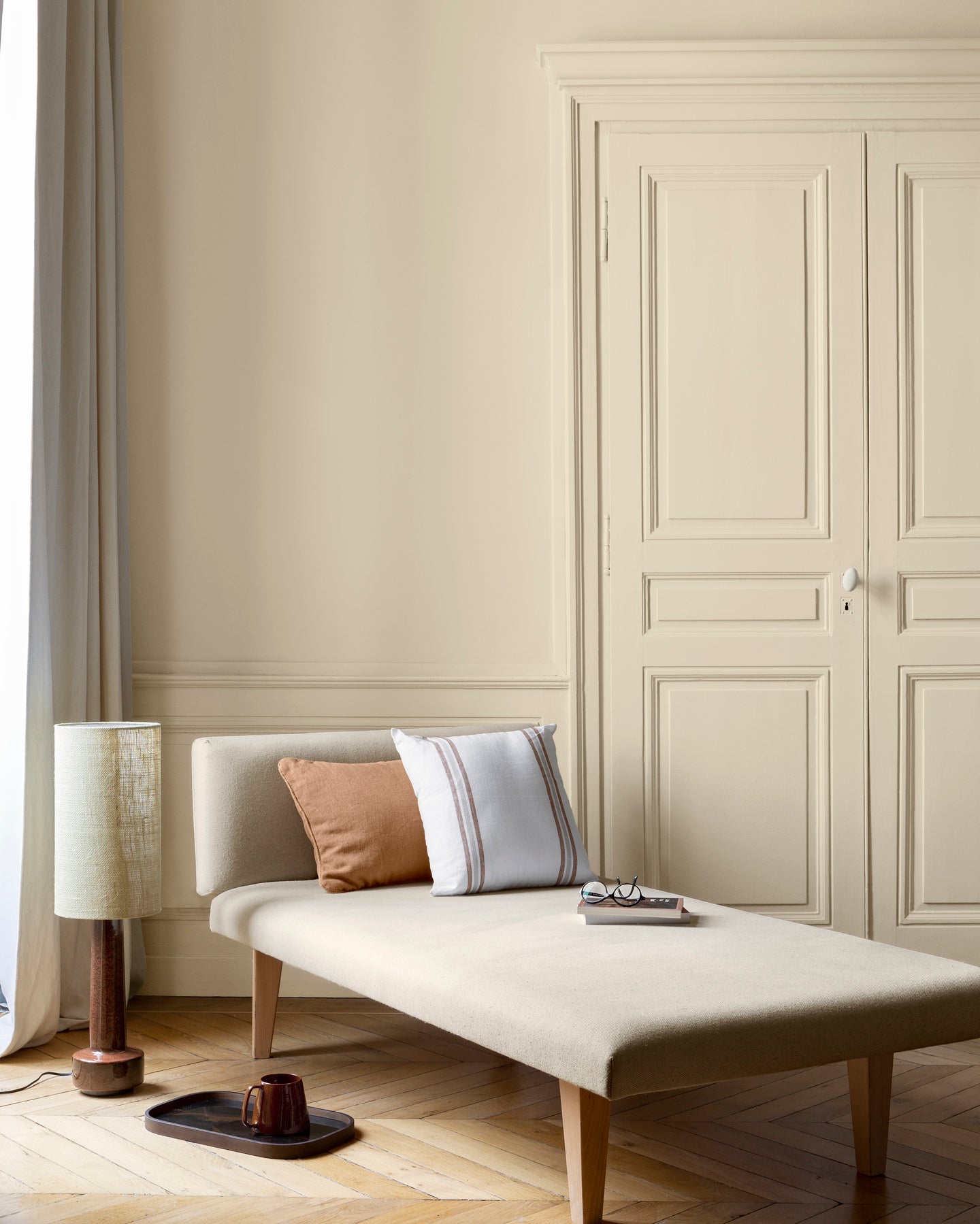 Salon aux murs Crème Saint-Honoré 163 Faubourg Libéron, avec méridienne écrue, portes assorties et parquet clair.