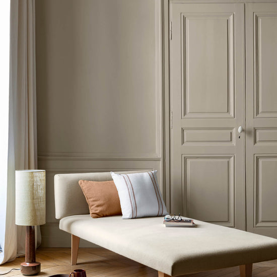 Salon aux murs grège galuchat Libéron, avec méridienne écrue, portes assorties, coussins terracotta et parquet clair.