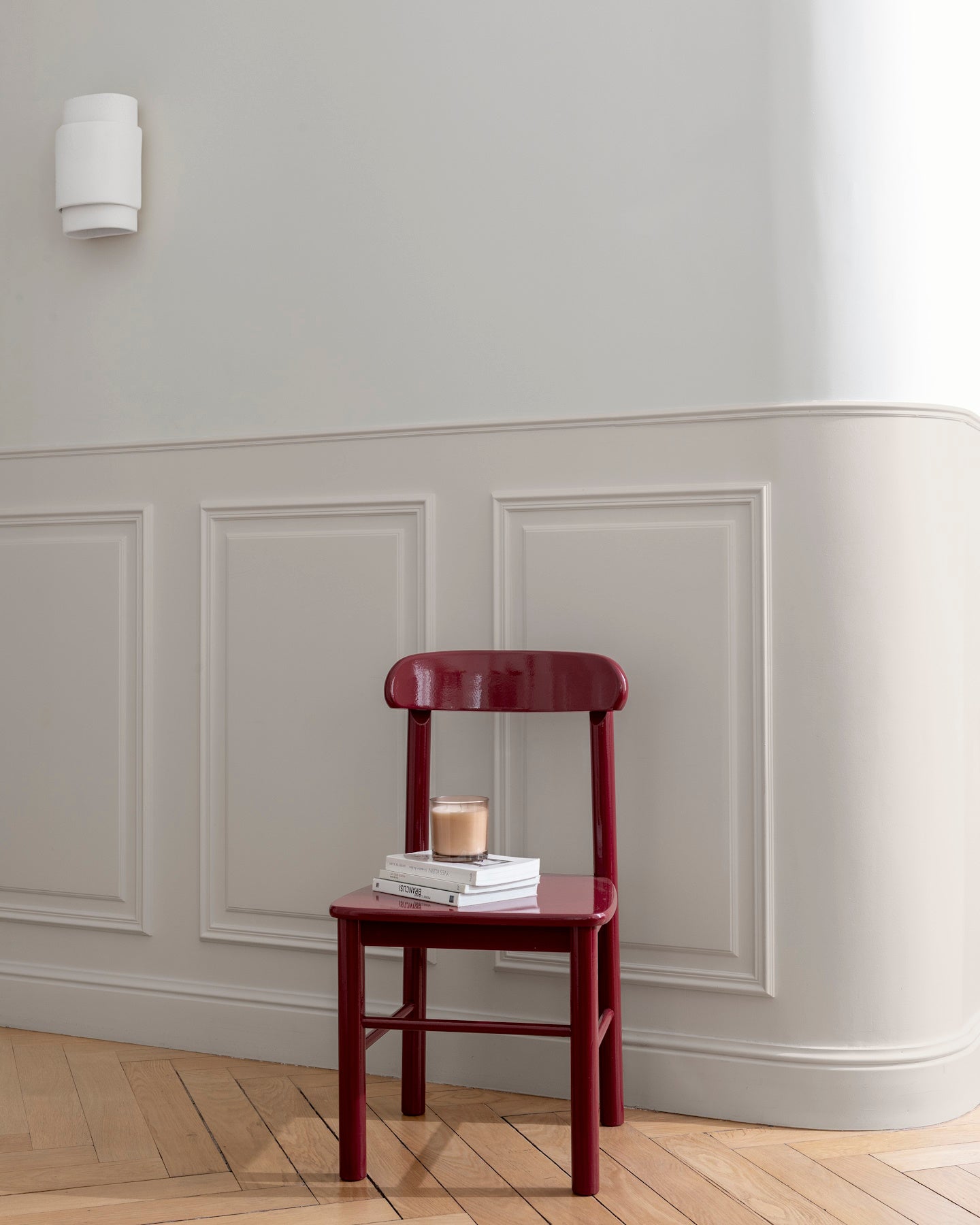 Mur grège tapissier et soubassement blanc grège Libéron, avec chaise Meuble signé rouge bordeaux brillant sur parquet.