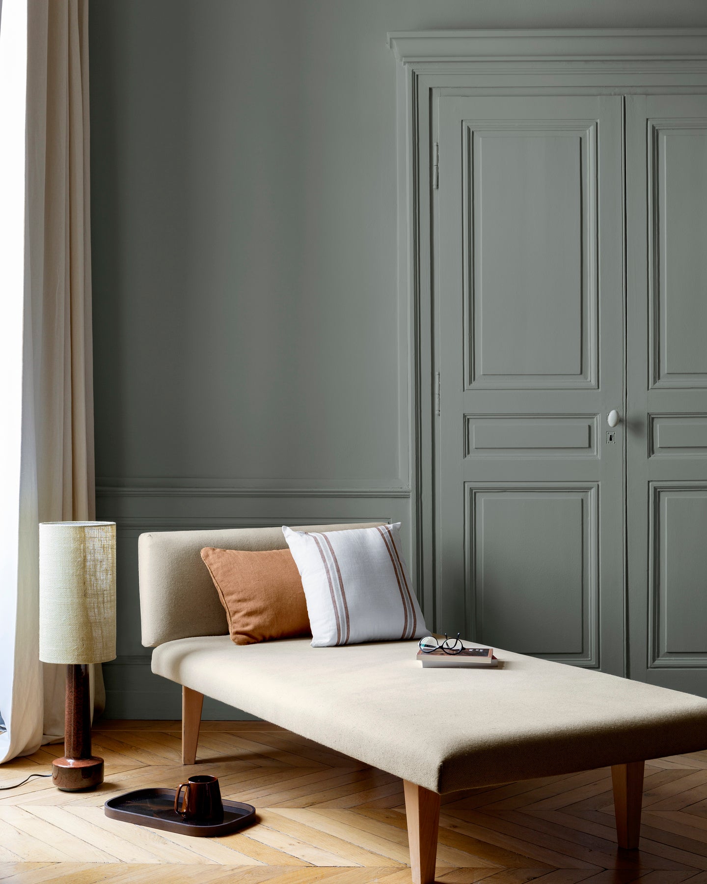 Salon lumineux avec porte et murs gris, peinture 163 Faubourg Gris Fabrique Libéron, avec méridienne blanche