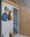 Entrée gris fer blanc Libéron avec escalier en bois clair, patères murales et coin salle de bain.