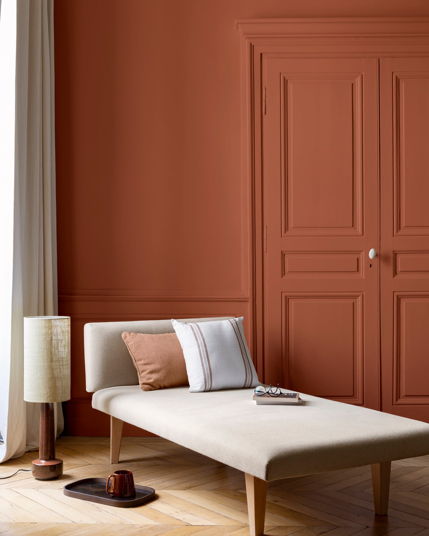 Salon lumineux avec porte et murs oranges, peinture 163 Faubourg Orange de Forge Libéron, avec méridienne blanche