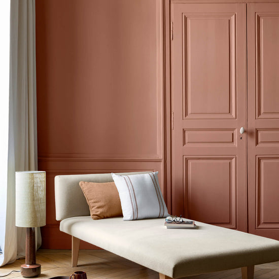 Salon lumineux avec porte et murs oranges, peinture 163 Faubourg Pêche Cancan Libéron, avec méridienne blanche