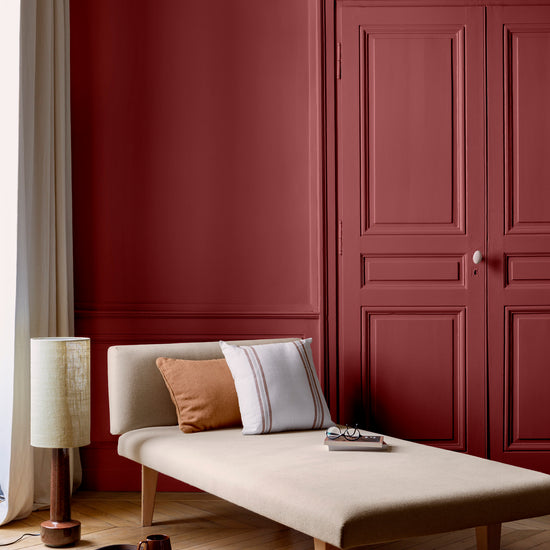 Salon lumineux avec porte et murs rouges, peinture 163 Faubourg Rouge Lyrique Libéron, avec méridienne blanche