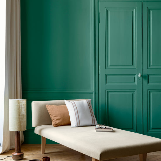 Salon aux murs Vert Émeraude Libéron, avec méridienne écrue, portes assorties, coussins terracotta et parquet clair.