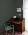 Coin bureau teint avec La Teinte Antiquaire Chêne Foncé Libéron, chaise, lampe et murs verts, et cadre accroché au mur