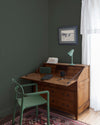 Coin bureau teint avec La Teinte Antiquaire Merisier Libéron, chaise, lampe et murs verts, et cadre accroché au mur