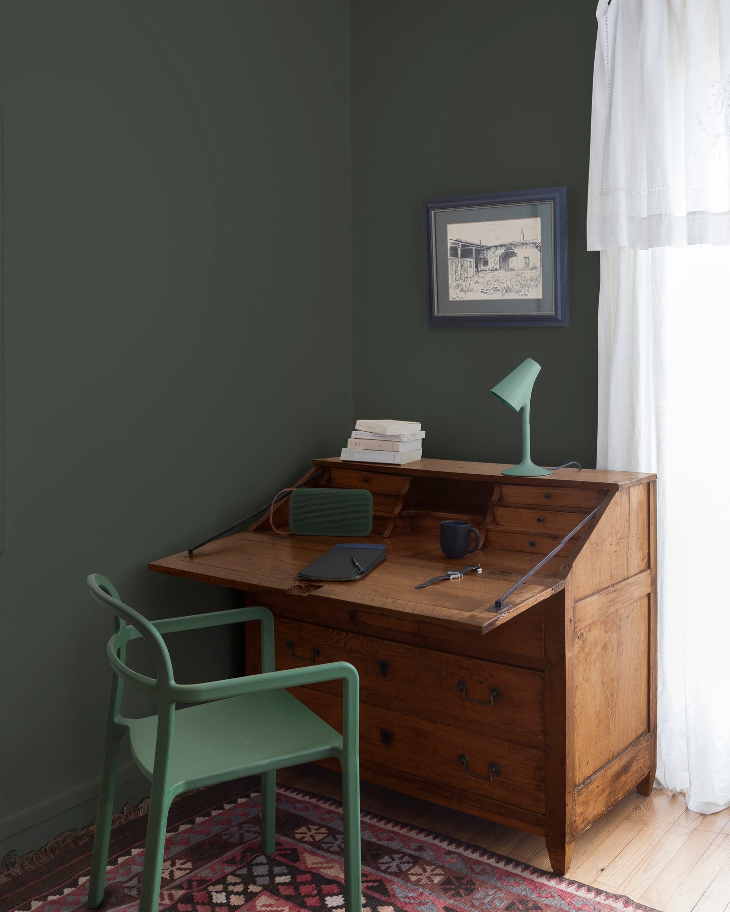 Coin bureau teint avec La Teinte Antiquaire Merisier Libéron, chaise, lampe et murs verts, et cadre accroché au mur