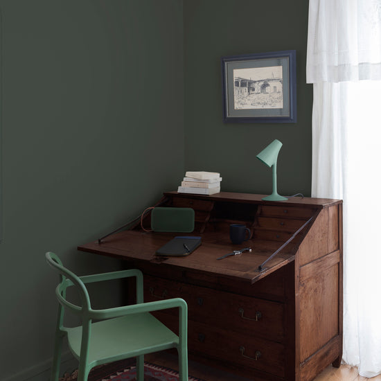 Coin bureau teint avec La Teinte Antiquaire Palissandre Libéron, chaise, lampe et murs verts, et cadre accroché au mur