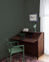 Coin bureau teint avec La Teinte Antiquaire Palissandre Libéron, chaise, lampe et murs verts, et cadre accroché au mur