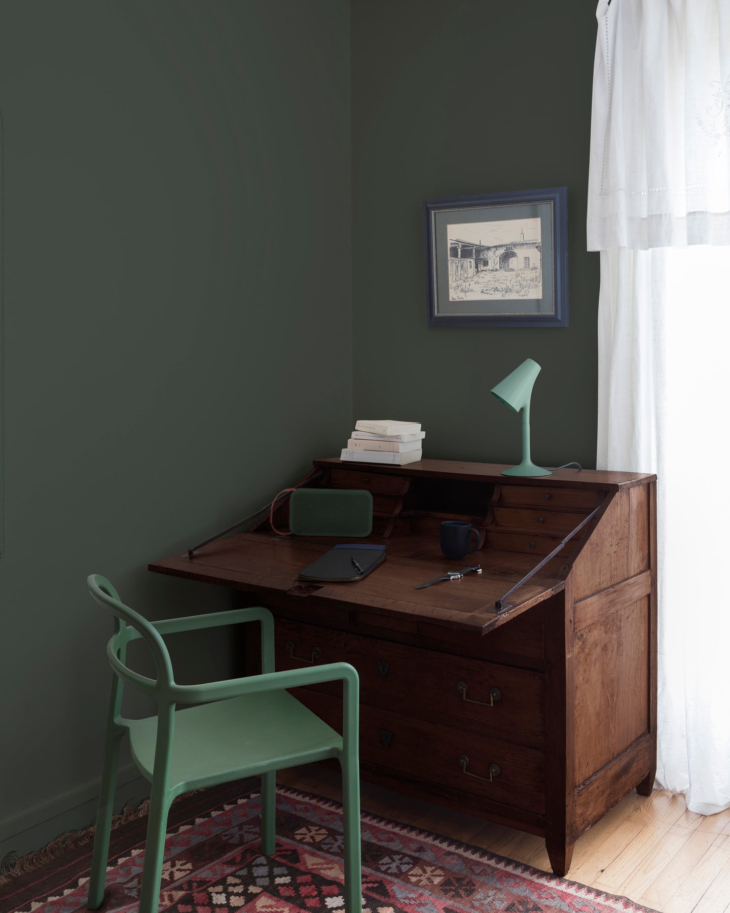 Coin bureau teint avec La Teinte Antiquaire Palissandre Libéron, chaise, lampe et murs verts, et cadre accroché au mur