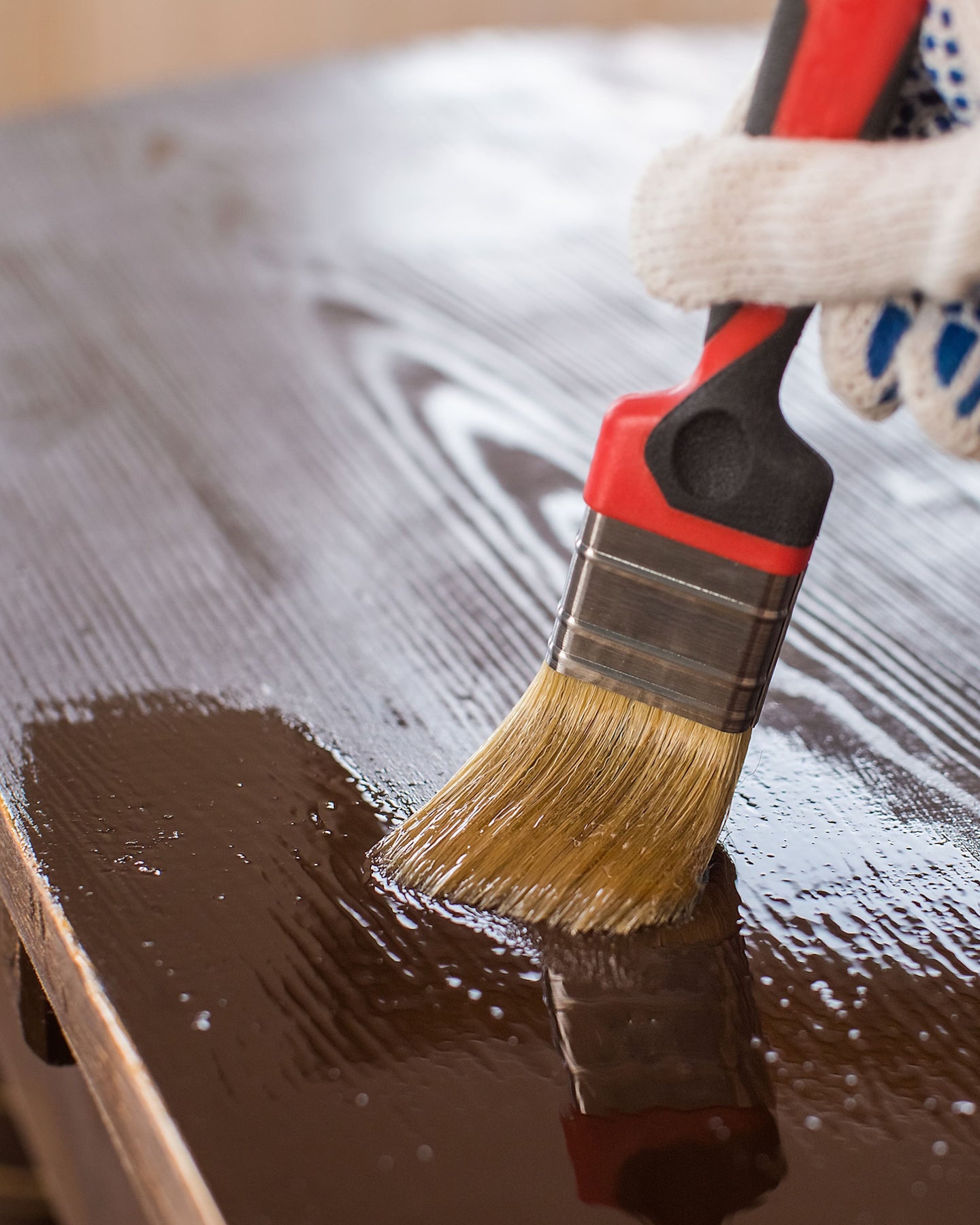 Main appliquant le Traitement Meubles et Boiseries Libéron au pinceau sur une surface en bois
