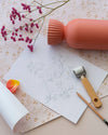 Détail de papier peint floral Belle Jeanne Libéron, avec vase corail, fleurs roses, dessin botanique et petit rouleau.