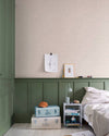 Chambre aux murs Florette Libéron, avec papier peint crème à petit motif vert, soubassement vert sauge, lit clair et valises pastel.
