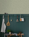 Entrée au mur Florette Libéron, avec papier peint crème à petit motif bleu, soubassement vert foncé, banc en bois et patères.