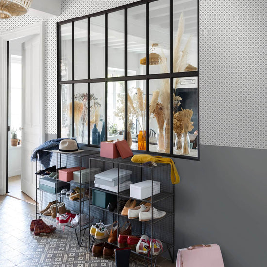 Entrée au mur à motif géométrique Maître Domino Libéron, avec soubassement gris, verrière noire et rangements ouverts.