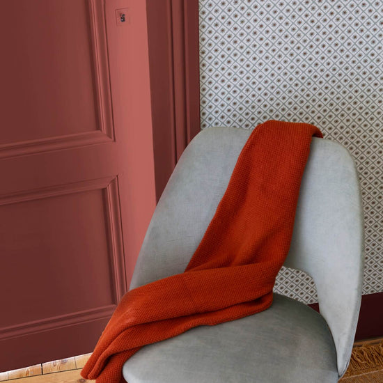Détail d’entrée avec porte terracotta, motif géométrique Maître Domino Libéron, chaise grise et plaid rouille.