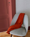 Détail d’entrée avec porte terracotta, motif géométrique Maître Domino Libéron, chaise grise et plaid rouille.