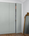 Armoire à motif géométrique Maître Domino Libéron, avec miroir doré posé au sol et parquet en bois clair.