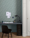Bureau au mur floral vert d’eau et blanc, teinte Œillet Reine Libéron, avec chaise noire, lampe noire et soubassement bleu.