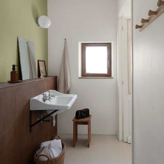 Salle de bain avec un lavabo suspendu, un soubassement en bois et des murs peints avec la peinture Libéron Velours de Peinture, teintes Argile Verte et Monnaie du Pape.