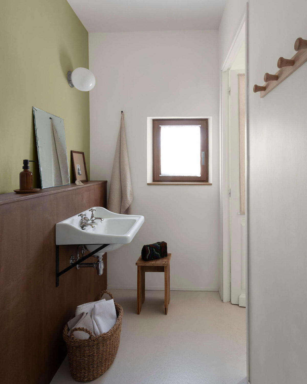Salle de bain avec un lavabo suspendu, un soubassement en bois et des murs peints avec la peinture Libéron Velours de Peinture, teintes Argile Verte et Monnaie du Pape.