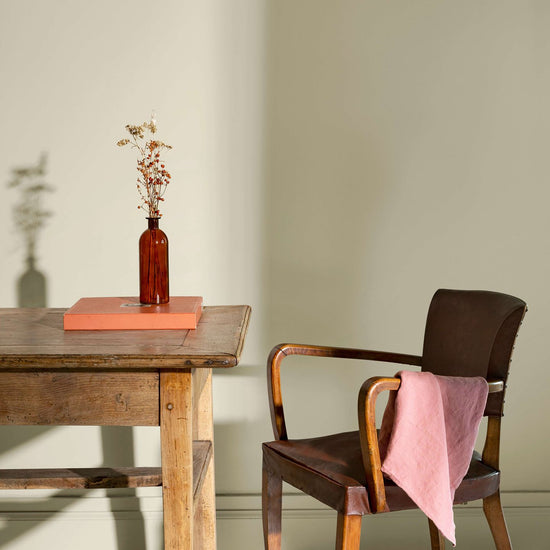 Coin de bureau avec une table rustique en bois, une chaise en cuir et des murs peints avec la peinture Libéron Velours de Peinture, teinte Beige Bouillon.
