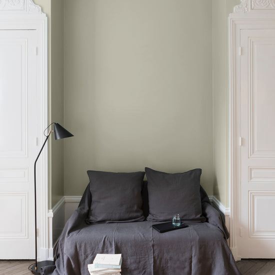 Salon aux murs beige bouillon, Velours de Peinture Libéron, avec canapé gris, portes blanches et parquet clair.