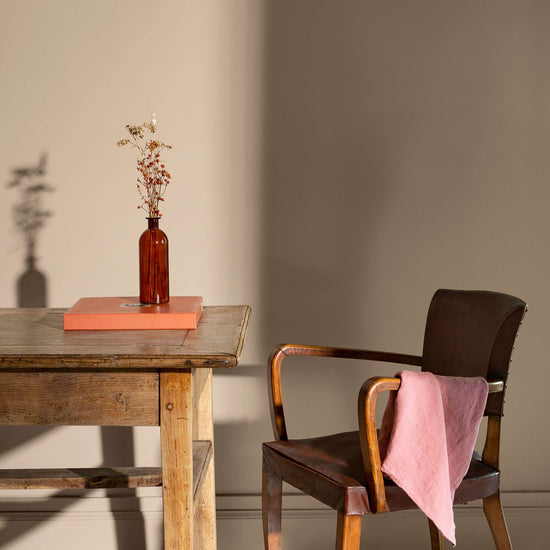 Coin de bureau avec une table rustique en bois, une chaise en cuir et des murs peints avec la peinture Libéron Velours de Peinture, teinte Beige Paris-Brest.