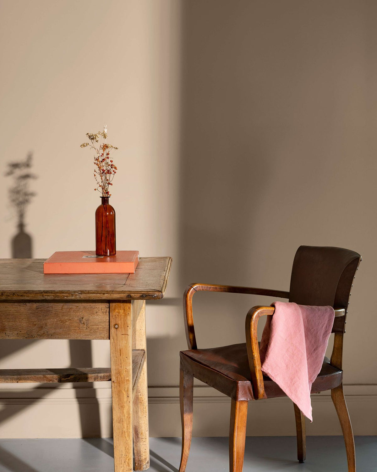 Coin de bureau avec une table rustique en bois, une chaise en cuir et des murs peints avec la peinture Libéron Velours de Peinture, teinte Beige Paris-Brest.