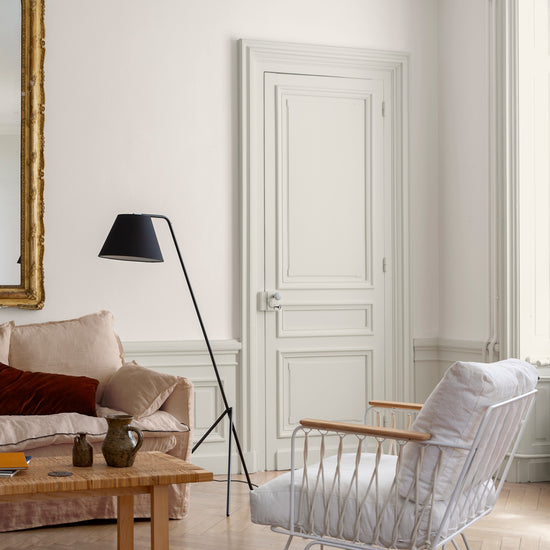 Salon aux murs blancs, peinture Velours de Peinture Blanc Camélia Libéron, avec porte blanche moulurée et canapé beige