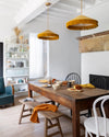 Salle à manger chaleureuse aux murs blancs, peinture Velours de Peinture Blanc Chiffon Libéron, lustres jaunes et table en bois