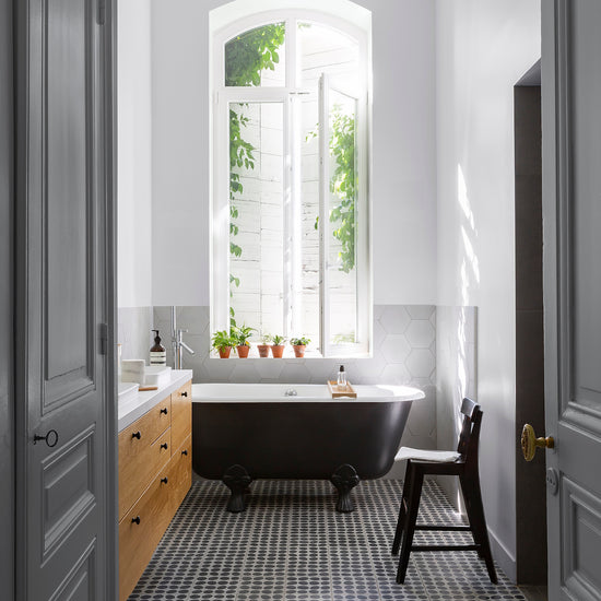 Salle de bain ensoleillée aux murs blancs, peinture Velours de Peinture Blanc Dépoli Libéron, baignoire noire et meuble en bois