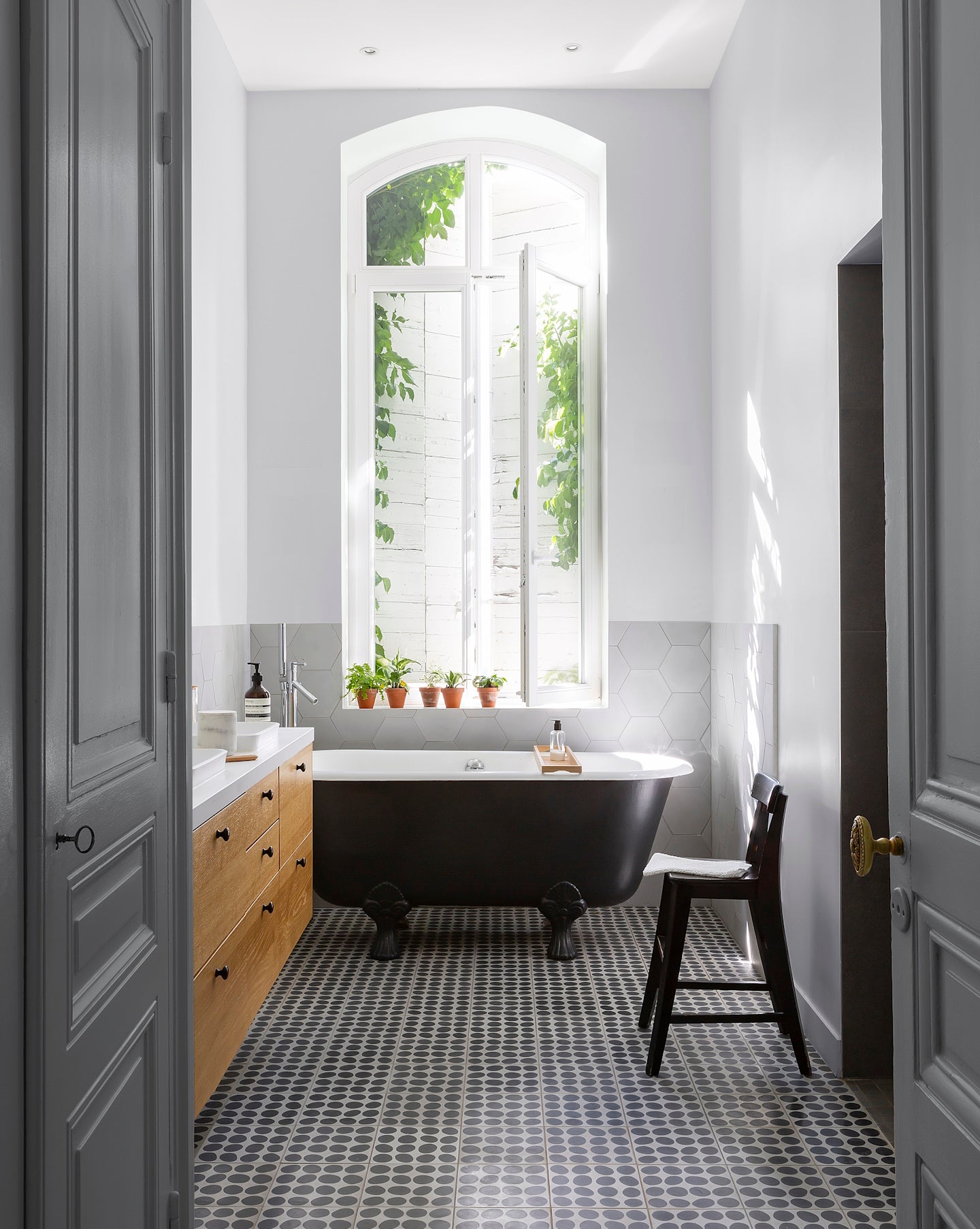 Salle de bain ensoleillée aux murs blancs, peinture Velours de Peinture Blanc Dépoli Libéron, baignoire noire et meuble en bois