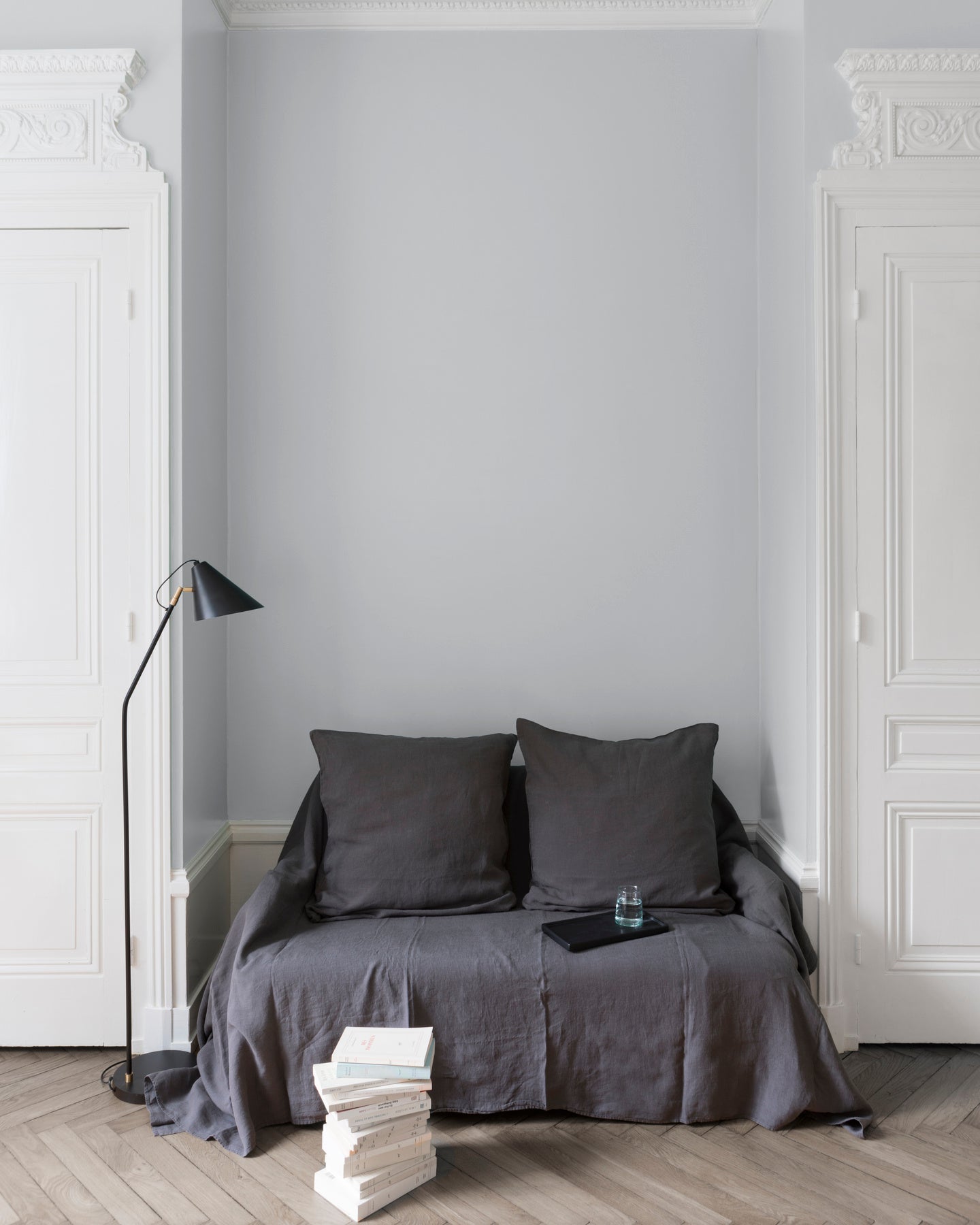 Salon aux murs blanc dépoli, Velours de Peinture Libéron, avec canapé gris, portes blanches et parquet clair.