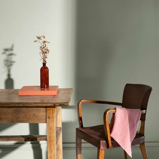 Coin de bureau avec une table rustique en bois, une chaise en cuir et des murs peints avec la peinture Libéron Velours de Peinture, teinte Blanc Edelweiss.