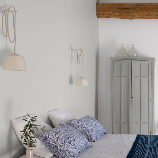 Chambre ambiance maritime aux murs blancs, Velours de Peinture Blanc Grisaille Libéron, linge de lit blanc et bleu et poutres en bois