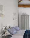 Chambre ambiance maritime aux murs blancs, Velours de Peinture Blanc Grisaille Libéron, linge de lit blanc et bleu et poutres en bois