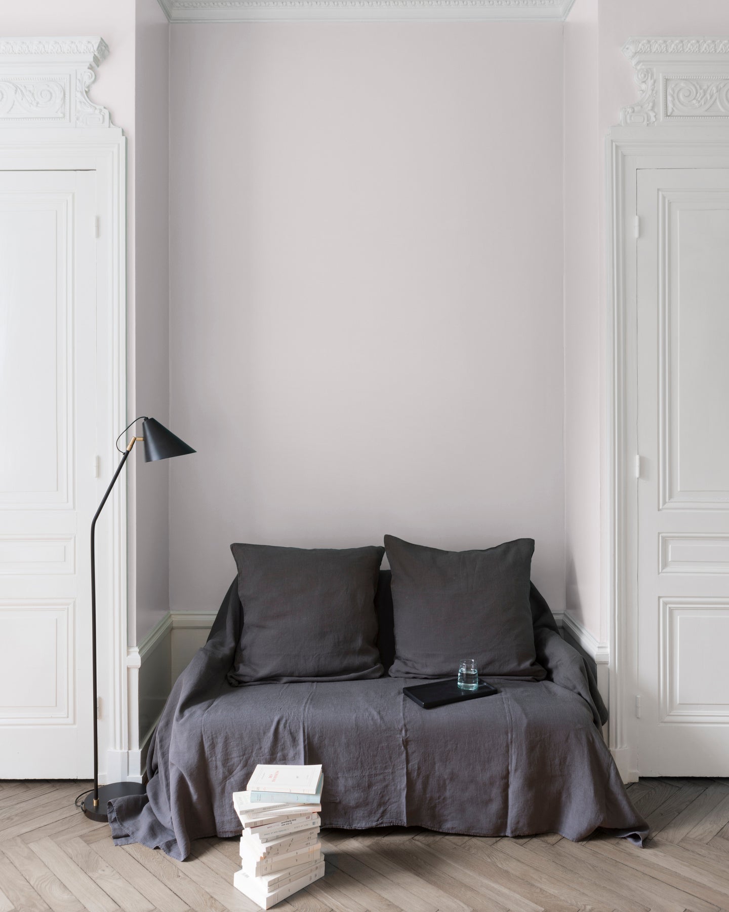 Salon aux murs blanc patisson Libéron, avec canapé gris, portes blanches, lampadaire noir et parquet clair.