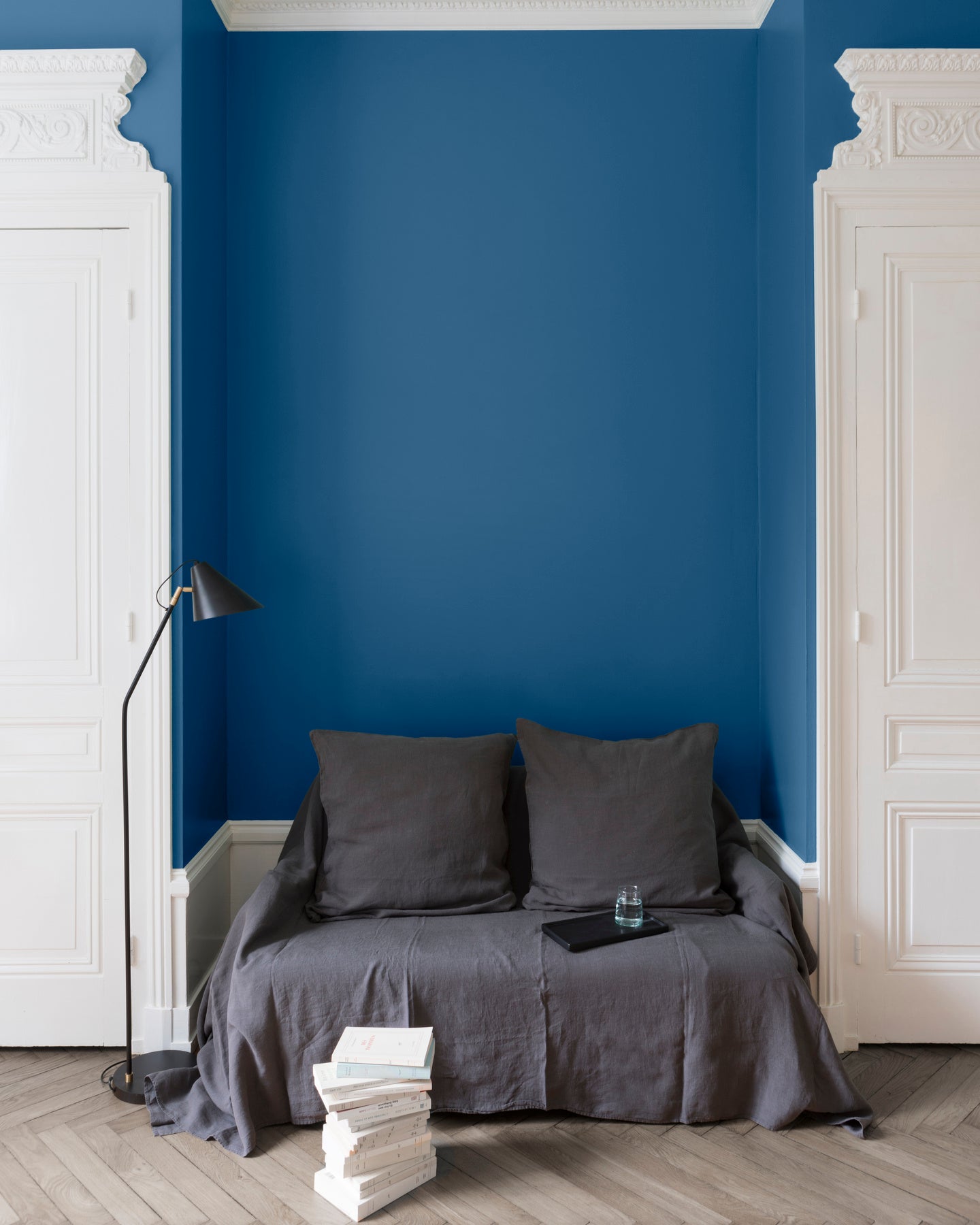Salon aux murs bleus, peinture Velours de Peinture Bleu d'Iroise Libéron avec portes blanches et textiles gris.