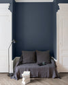 Salon aux murs bleu de chauffe, Velours de Peinture Libéron, avec canapé gris, portes blanches et parquet clair.
