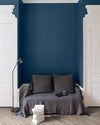 Salon aux murs bleu de minuit, Velours de Peinture Libéron, avec canapé gris, portes blanches et parquet clair.