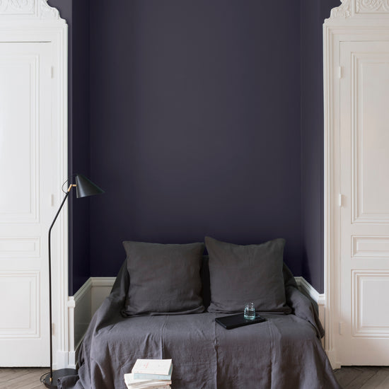 Salon aux murs bleu de Sèvres Libéron, avec canapé gris, portes blanches, lampadaire noir et parquet clair.