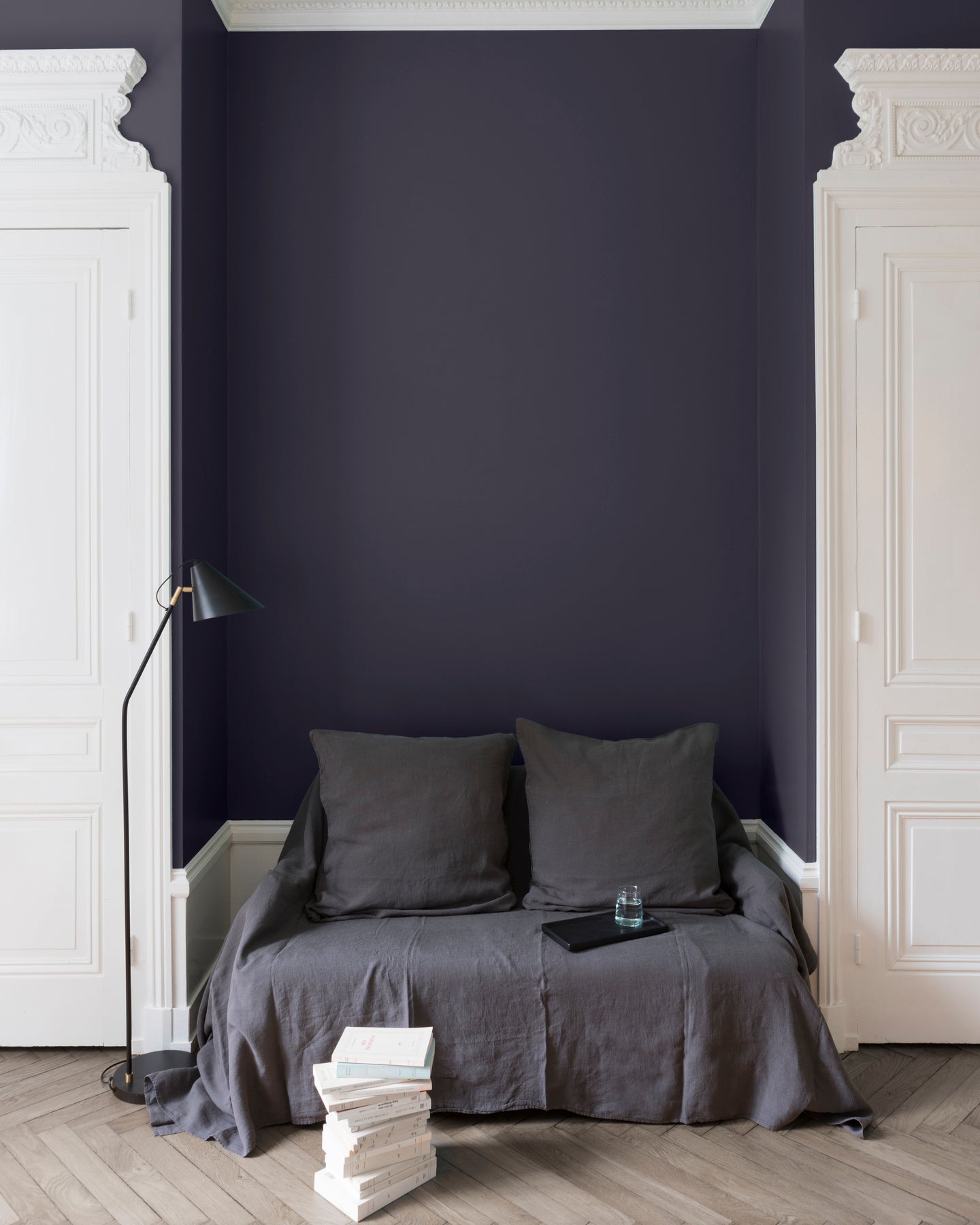 Salon aux murs bleu de Sèvres Libéron, avec canapé gris, portes blanches, lampadaire noir et parquet clair.