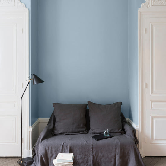 Salon aux murs bleus, peinture Velours de Peinture Bleu Embruns Libéron avec portes blanches et textiles gris.