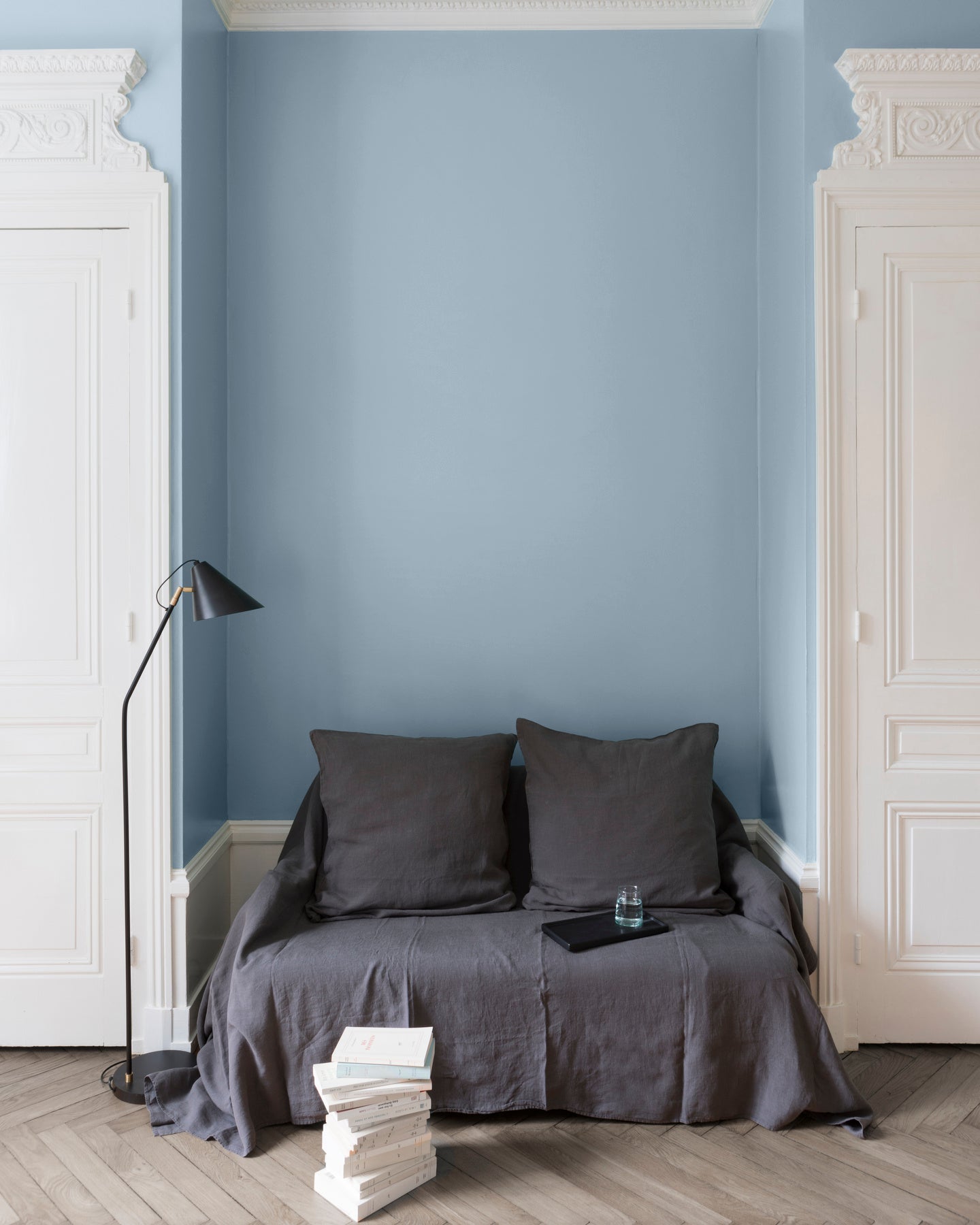 Salon aux murs bleus, peinture Velours de Peinture Bleu Embruns Libéron avec portes blanches et textiles gris.